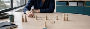 Eine Führungskraft untersucht ein Teammodell mit unterbrochenen Verbindungen, getrennten Gruppen und einer isolierten Figur.