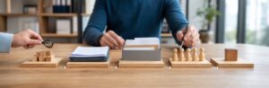 Realistische Arbeitsszene zum Thema «Submissionsverfahren Schritt für Schritt: Von der Bedarfsanalyse bis zum Zuschlag»: 1. Bedarfsanalyse, 2. Ausschreibung, 3. Angebotseingabe, 4. Bewertung, 5. Zuschlag.